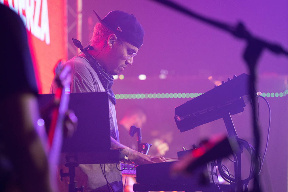 DJ facing a crowd at his deck. Photo with a purple hue